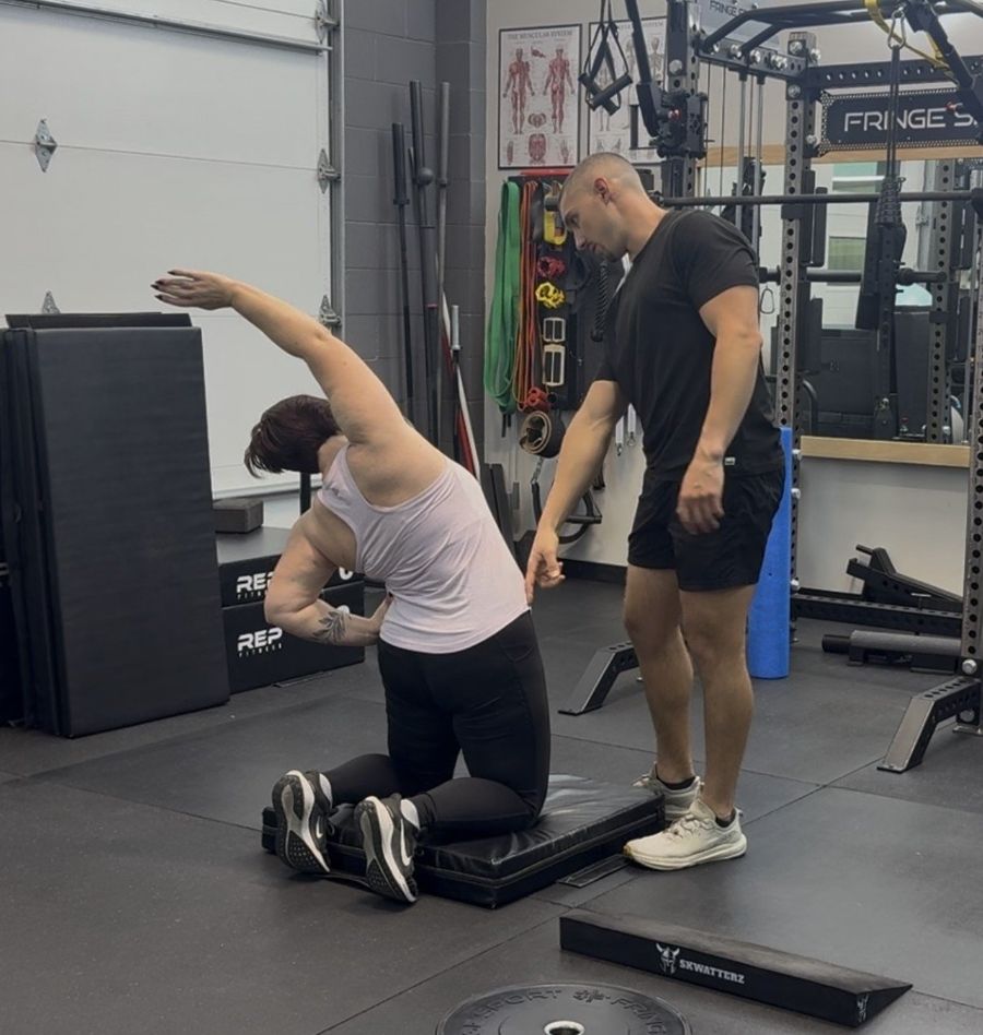 Coach guiding a client through a kneeling stretch